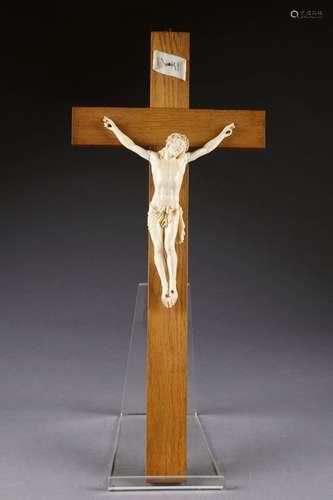 Christ. Couronné d'épines, la tête tournée vers la gauche, le périzonium retenu par une cordelette, les pieds superposés. Ivoire finement sculpté. XIXe siècle.<br/>Hauteur: 26 cm. Présenté sur une croix en chêne.<br/>Hauteur totale: 64 cm. Condition. Petits manques aux doigts des mains.