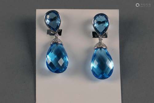 Paire de Pendants d'Oreilles. Sertis de quatre topazes bleues taille briolet (env. 56 carats) et agrémentées de petits diamants taille brillant (env. 0 carat 46). Monture en or blanc 18 carats.<br/>Poids: 16,7 gr.