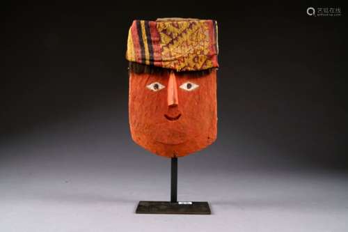 Masque Chancay aux Formes schématisées. Visage peint en rouge et yeux losangés de part et d'autre d'un nez proéminent. Coiffe en tissu à motifs géométriques. Pérou. 1100 à 1400 ans après Jésus-Christ.<br/>Hauteur: 32 cm. Sur socle. Sans certificat.