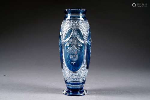 Sur un modèle de Joseph Simon. Vase fuselé sur pied hexagonal. Cristal incolore, doublé bleu, taillé de guirlandes de drapés sur fond étoilé.<br/>Hauteur: 25,5 cm. Condition: Pas d'accident ni de restauration.