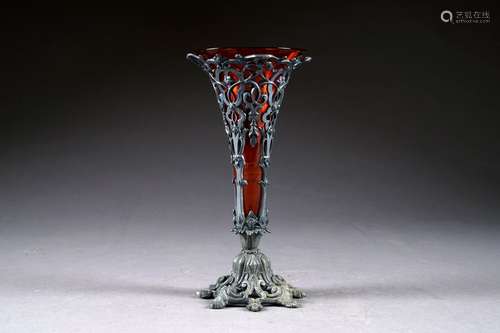 Verre teinté rouge à monture à palmettes ajourées en métal argenté. XIXe siècle.<br/>Hauteur: 25 cm.