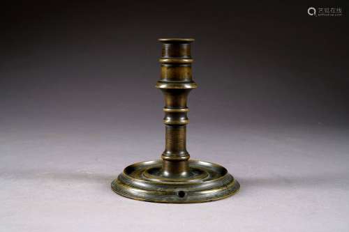 Bougeoir<br/>Fût et binet à épaulement portés par un pied rond mouluré à petite galerie.<br/>Bronze patiné. XVIIIe siècle.<br/>Hauteur: 19 cm.