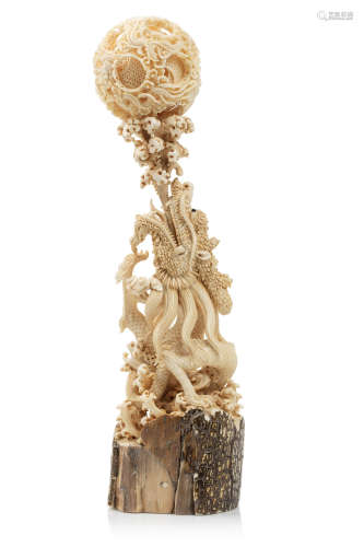 Chine, 2ème moitié du XXe siècle  Boule de Canton en ivoire de mammouth* finement sculpté de dragons, reposant sur un socle