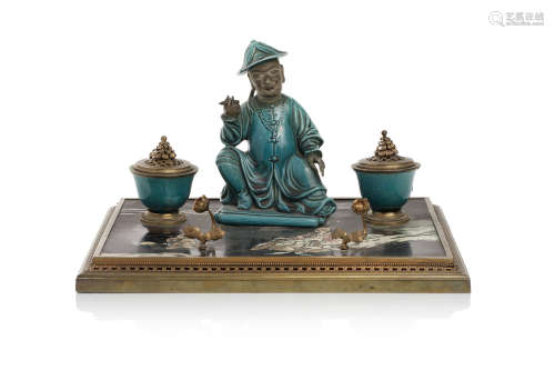 Chine, XIXe siècle.  Encrier composé d’un magot en biscuit émaillé bleu turquoise et deux petites coupes ornées de couvercles en bronze doré, reposant sur un panneau en laque de coromandel, le socle en bronze doré orné de motifs en guirlande.