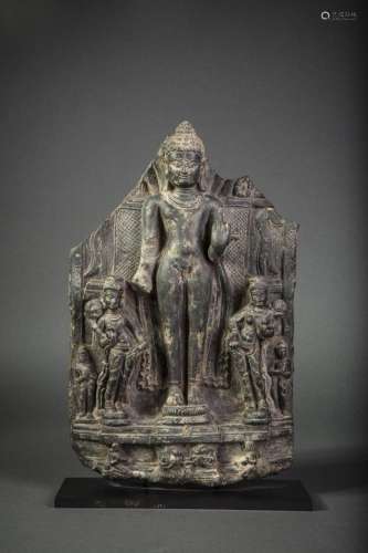 Stèle illustrant Buddha debout en abayamudra accompagné de deux apsaras tenant des lotus grimpant et de quatre adorants, deux debout et deux agenouillés à la base.