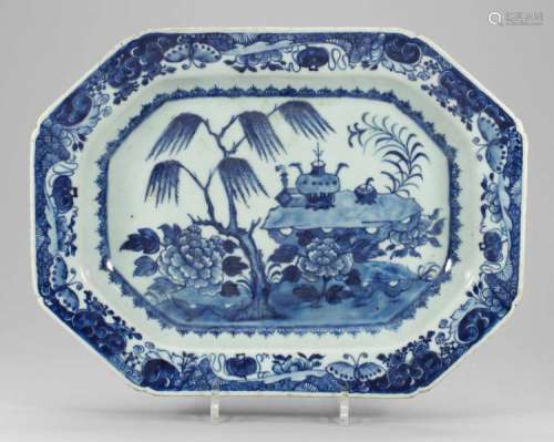 Plat octogonal de la Compagnie des Indes en porcelaine blanche décorée en bleu cobalt sous couverte de vases d’offrandes dans un jardin impérial.