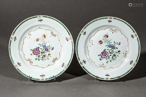 Paire d'assiettes en porcelaine famille rose de la Compagnie des Indes décorées en fond d'un bouquet fleuri autour d'une guirlande polylobée et d'une frise géométrique parsemée de violettes au marli.