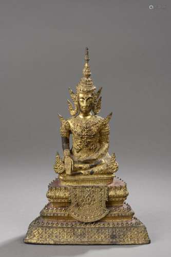 Buddha Maravijaya richement paré coiffé d'une haute tiare à ailettes buddha assis sur un haut socle étagé d’où pend une bannière.