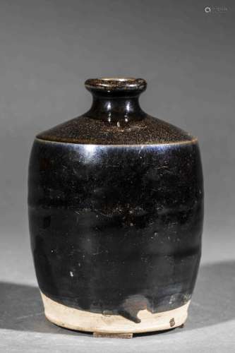 Flacon sur base plate à épaulement oblique et col cylindrique ourlé en grès porcelaineux à glaçure monochrome noire nuancé au brun.