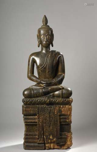 Buddha assis en virasana sur un haut socle à base lotiforme d'où pend une bannière, vêtu d'une robe monastique utarasanga les deux mains dans son giron en abayamudra, coiffé d'une haute flamme surmontant la protubérance crânienne ushnisha.