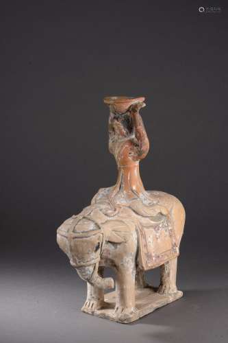 Acrobate chevauchant un éléphant harnaché portant une coupe sur sa tête.