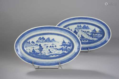 Paire de plats ovale de la Compagnie des Indes en porcelaine décoré en bleu cobalt sous couverte sur fond blanc d'un paysage lacustre animée de pagodes et embarcations.