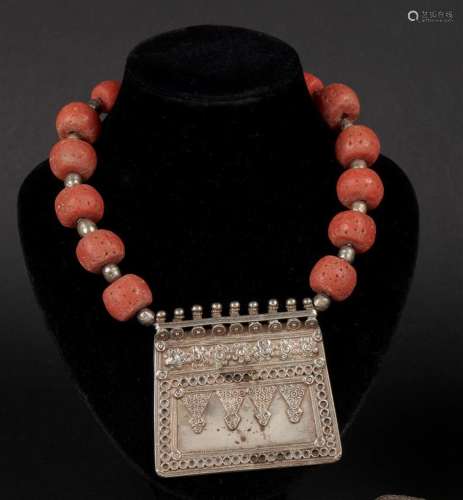 COLLIER ethnique en boules de couleur corail et boules de métal, il est orné d'un pendentif plastron à décor ciselé de pastilles. Poids brut: 246 g