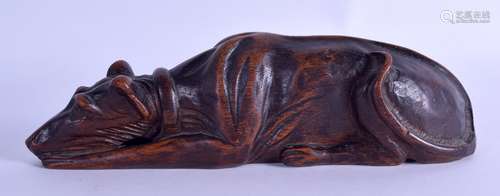 A 19TH CENTURY CONTINENTAL CARVED OAK FIGURE OF A STYLISED HOUND modelled recumbent 23 cm long.