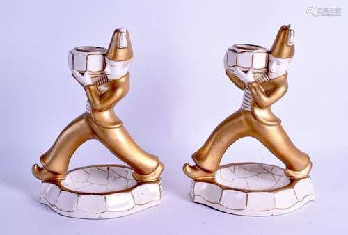 AN UNUSUAL PAIR OF ART DECO CONTINENTAL PORCELAIN CANDLESTICKS modelled as a males roaming across