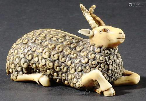 IVORY CARVING OF AN ANGORA GOAT, probably Japanese and 19th century, recumbent, inset with amber