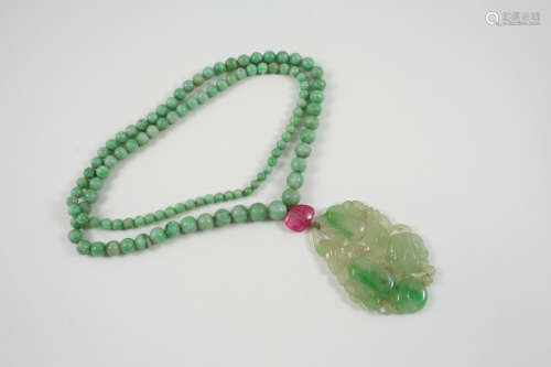 A CARVED AND PIERCED JADE PENDANT of foliate design, and suspended from a jade bead necklace, the