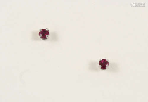 A PAIR OF RUBY STUD EARRINGS each earring set with a circular-cut ruby in white gold.