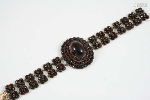 A VICTORIAN GARNET BRACELET the central oval garnet cabochon is set within a triple surround of