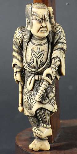 JAPANESE IVORY NETSUKE, carved as a samurai holding his sword, 10cm