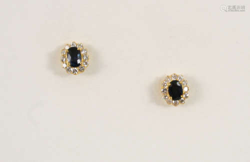 A PAIR OF SAPPHIRE AND DIAMOND CLUSTER STUD EARRINGS each set with an oval-shaped sapphire within