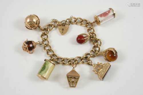 A 9CT. GOLD CURB LINK CHARM BRACELET with padlock clasp and suspending assorted charms, including