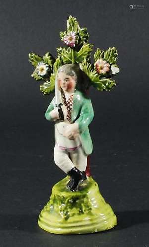 PEARLWARE FIGURE, circa 1800, of a man standing holding up a sword before a bocage, height 14cm