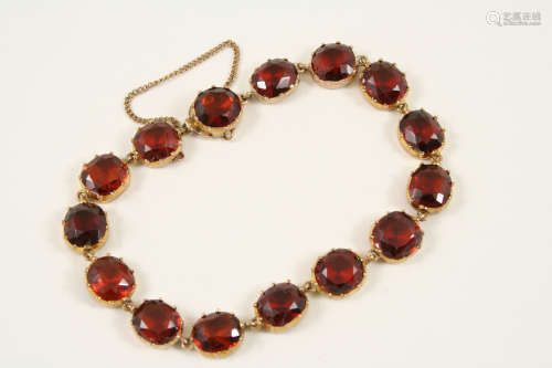 A GARNET BRACELET formed with oval-shaped garnets in gold cut down collet settings, 18cm. long.