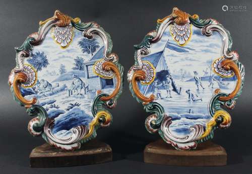 PAIR OF DUTCH DELFT PLAQUES, 19th century, painted with summer and winter scenes inside scrolling