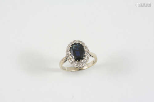 A SAPPHIRE AND DIAMOND CLUSTER RING the oval-shaped sapphire is set within a surround of circular-