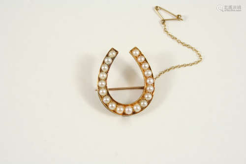 A GOLD AND PEARL SET HORSESHOE BROOCH set with graduated half pearls, 2.5cm. wide.