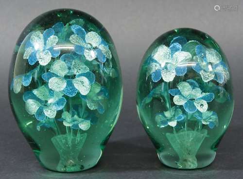 TWO GREEN GLASS DUMPS, of typical form, both with a spray of silver and blue petalled flowers,