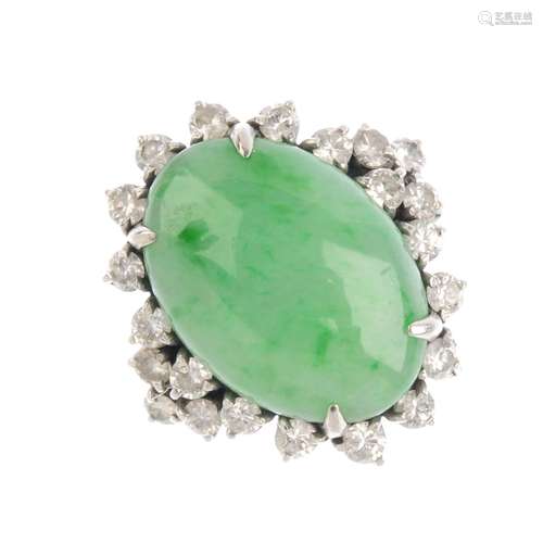 A jade and diamond cluster ring. The oval jadeite cabochon, with brilliant-cut diamond surround