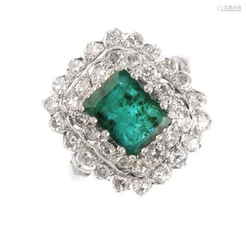 An emerald and diamond cluster ring. The rectangular-shape emerald, within an old-cut diamond double