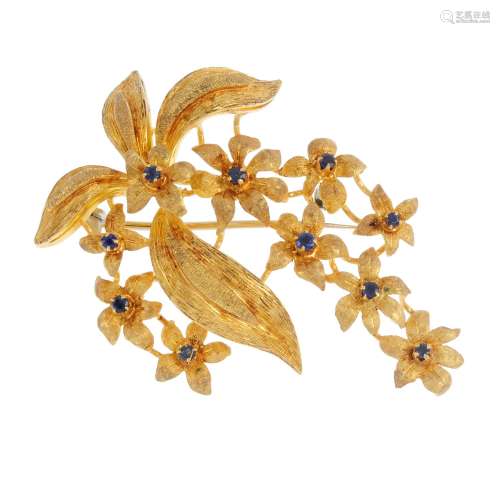 A sapphire floral brooch. Designed as a series of circular-shape sapphire accent flowers, with