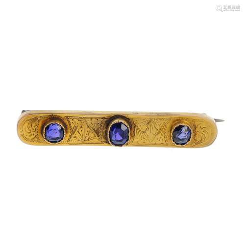 A sapphire bar brooch. The graduated oval-shape sapphire line, with engraved surround. Length 4.