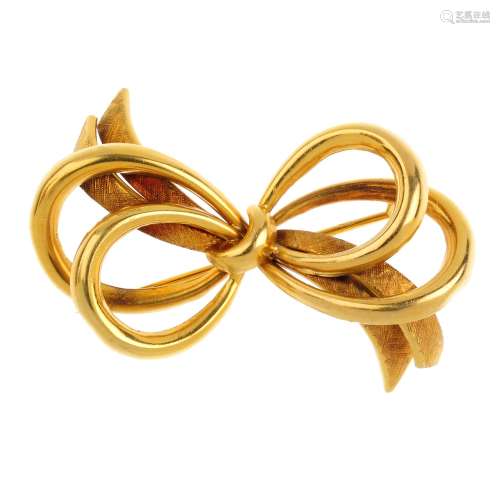 An 18ct gold bow brooch. Designed as a polished asymmetric curved bow, with textured ribbon