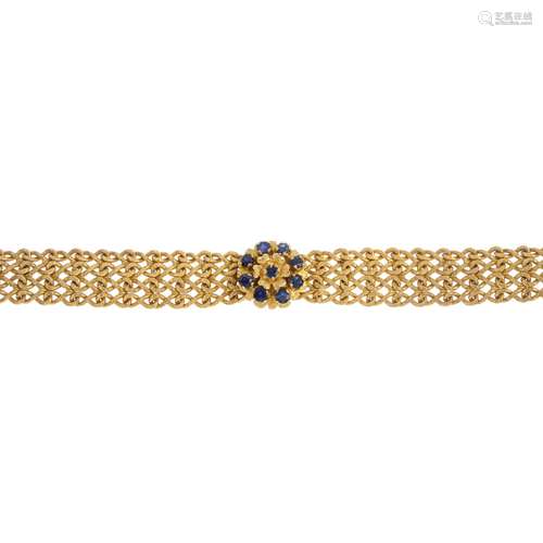 A sapphire bracelet. The circular-shape sapphire accent floral cluster, atop the textured fancy-link