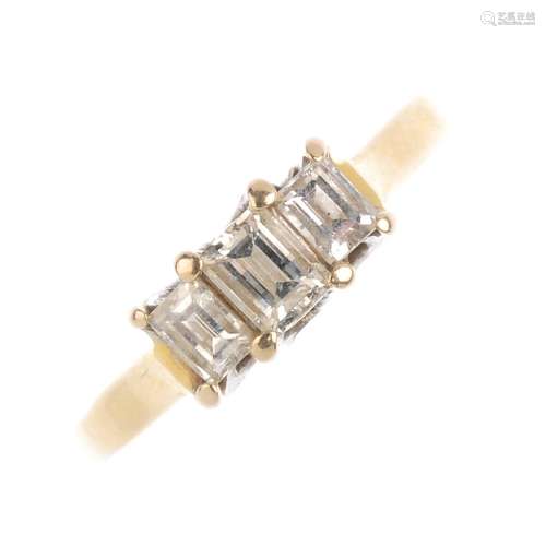 (52273) An 18ct gold diamond three stone ring. The graduated baguette-cut diamond line, with plain