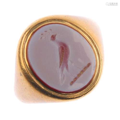 A gem-set signet ring. The oval carnelian, carved to depict bird and foliate motif, with tapered