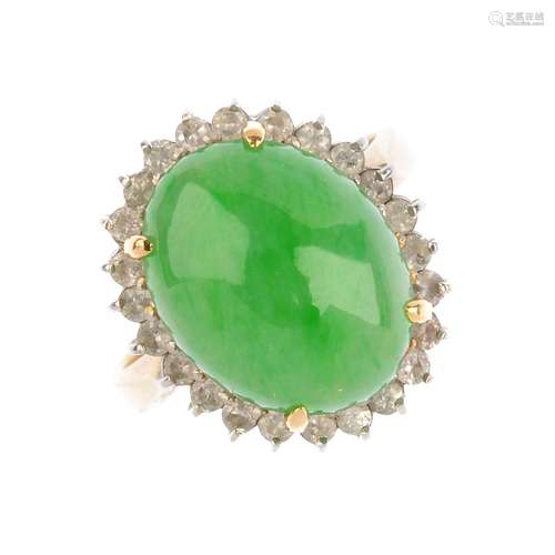 A jade and diamond dress ring. The oval jadeite cabochon, with brilliant-cut diamond surround and