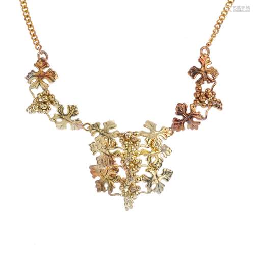 A 9ct gold necklace, designed as a bi-colour grape and vine motif panel, with similarly-designed