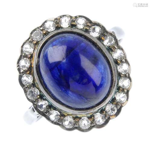 A glass-filled sapphire and paste cluster ring. The oval glass-filled sapphire cabochon, with