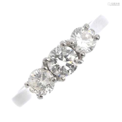 A platinum diamond three-stone ring. The brilliant-cut diamond, with similarly-cut diamond sides and