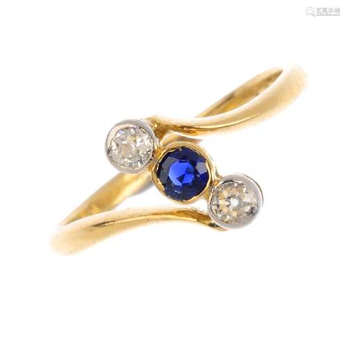 A sapphire and diamond crossover ring. The circular-shape sapphire and old-cut diamond off-set line,