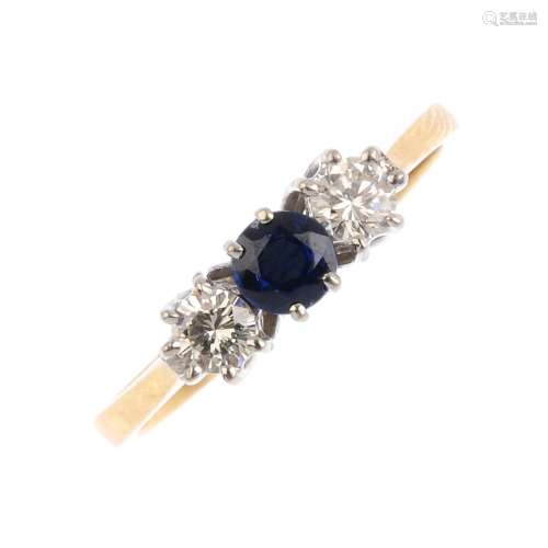 An 18ct gold sapphire and diamond three-stone ring. The circular-shape sapphire and brilliant-cut