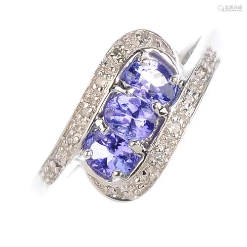 A 9ct gold tanzanite and diamond crossover ring. The oval-shape tanzanite line, with single-cut