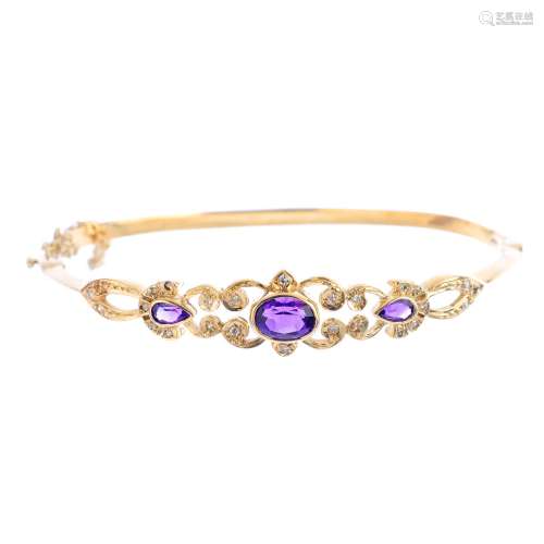 A 9ct gold amethyst and diamond hinged bangle. Of openwork design, the oval and pear-shape