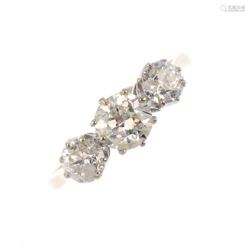 An 18ct gold diamond three-stone ring. The graduated old-cut and brilliant-cut diamond line, with