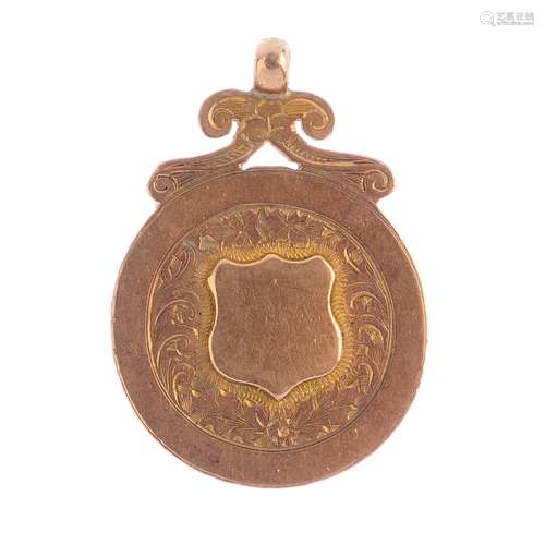 An early 20th century 9ct gold fob. Designed as an embossed shield, within a foliate panel border,